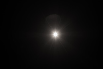 White flash spark on black background. Lens flare effect. Defocused spotlight glow