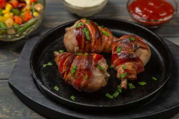 Fried chicken legs wrapped in bacon with vegetables