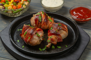 Fried chicken legs wrapped in bacon with vegetables