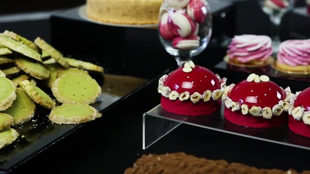 slow panorama on candy bar table with tasty green shortbreads, red mousse, pink marshmallows and macarrons