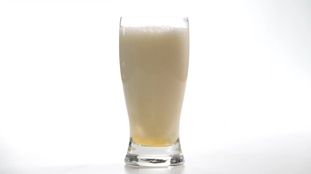 Cerveza cayendo en copa sobre fondo bllanco 4k