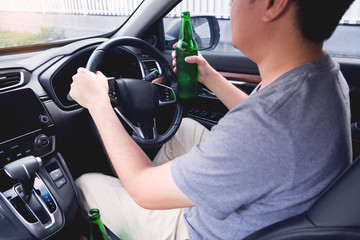 Don't Drink for Drive concept, Young Drunk man drinking bottle of beer or alcohol during driving the car dangerously