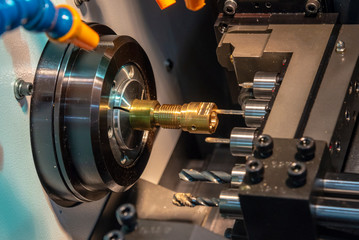 Fototapeta na wymiar The CNC lathe machine drilling the hole on the brass shaft part with drill tool. Hi-technology automotive part manufacturing process.