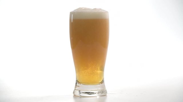 Cerveza cayendo en copa sobre fondo bllanco 4k