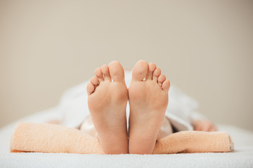 selective focus of adult woman lying on beige towel in spa