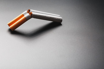 Two cigarettes in the form of a double-barreled shotgun on a black background with copy space. Stop smoking. The concept of smoking kills.
