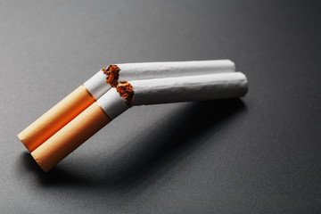 Two cigarettes in the form of a double-barreled shotgun on a black background with copy space. Stop smoking. The concept of smoking kills.