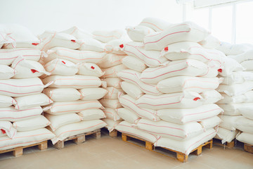 Folded white bags on pallets in factory storage.
