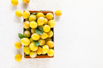 Fresh yellow plums. Ripe fruits in a wooden box on white background.