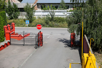 Industrial area. Factory zone. Green trees outdoors. Red stop sign on the road. Pedestrian place.