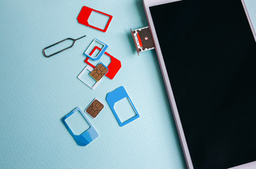 Modern smartphone lying on the table. Different micro and nano sim cards nearby. Different...