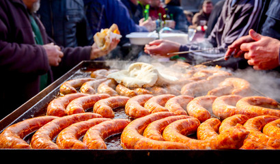 Turning delicious juicy sausages on barbecue plate with handle