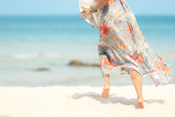 Fototapeta na wymiar Close up legs smiling lifestyle woman wearing fashion dress summer running on the sandy ocean beach. Happy woman enjoy and relax vacation. Lifestyle and Travel Concept