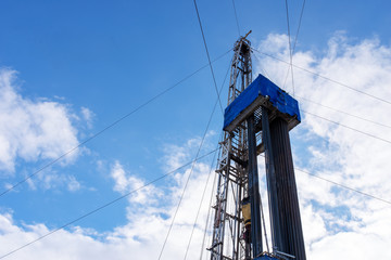 Oil and Gas Drilling Rig onshore dessert with dramatic cloudscape. Oil drilling rig operation on the oil platform in oil and gas industry. Land drilling rig blue sky