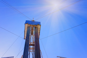 Fototapeta premium Oil and Gas Drilling Rig onshore dessert with dramatic cloudscape. Oil drilling rig operation on the oil platform in oil and gas industry. Land drilling rig blue sky