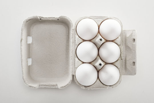 Top View Of Raw White Chicken Eggs In Carton Box On White Background