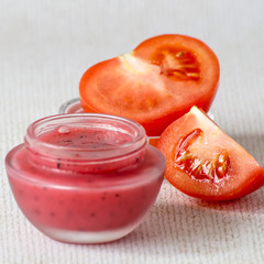 A small glass jar with a cosmetic face mask based on tomatoes on a light background. Selective...