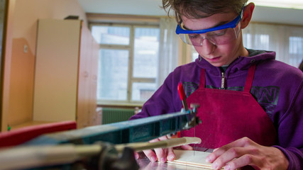 Young carpenter crafting from wood on table saw