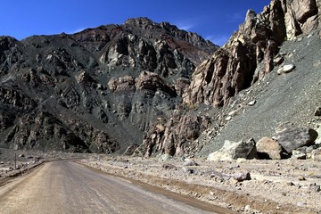 Dirt road leading through rugged mountains at pacific coast line to Pan de Azucar,  Atacama desert, Chile