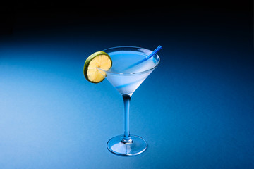 Classic Daiquiri cocktail with lime in martini glass on a dark blue background. Space for text.