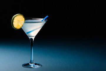 Classic Daiquiri cocktail with lime in martini glass on a dark blue background. Space for text.