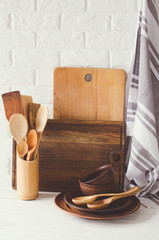 Ceramic plates, wooden or bamboo cutlery, cutting boards and towel in interior of kitchen.