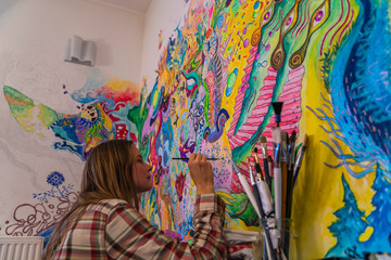 Young female artist doodling on the wall, bright psychedelic mind flow deep relaxation painting