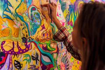 Young female artist using fingers while painting wall artwork