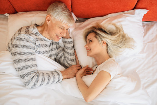 Mature love couple looks at each other in bedroom