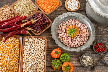 Legumes in the bowl and in the copper cookware on the rustic wooden table