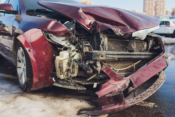 Vehicle showing front end damage from rear ending another vehicle at a red light.