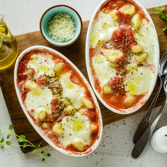 Italian potato dumplings gnocchi alla sorrentina with mozzarella cheese, baked in the oven with tomato sauce and herbs. Served with parmesan and spices. Classic healthy vegetarian cuisine