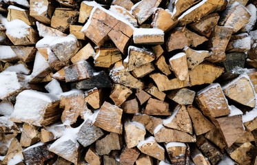 Firewood covered with snow. Preparation of firewood for the winter. firewood background, Stacks of firewood in the forest. Pile of firewood.