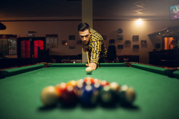 Male billiard player with cue aiming at the table - obrazy, fototapety, plakaty