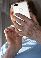 Hands of an old woman using a smartphone
