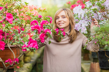 Beautiful woman watering plants and gardening in greenhouse.