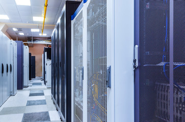 Room with rows of server hardware in big modern data center corridor. Technical equipment and...