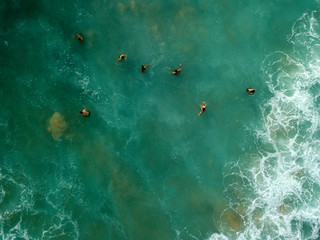 Aerial view of people swimming on waves in sea, ocean on Dreamland beach, Bali, Indonesia.