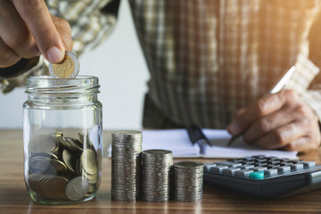 Business man putting the money in glass jar to saving,financial,accounting concept.