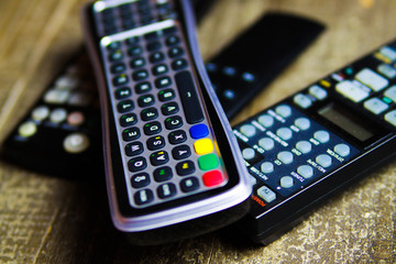 Close up of remote controls for TV, Video and stereo music system on wood table