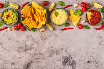 Mexican food background: guacamole, salsa, cheesy sauces with nachos