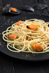 Mussel spaghetti on black wooden table.