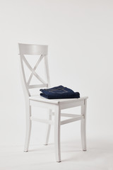 Wooden chair with folded denim pants on white