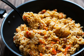 Traditional homemade Uzbek pilaf or plov in iron frying pan. Uzbek cuisine. Close Up. Selective Focus.