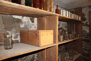 Fototapeta na wymiar An old shelf in a basement, with empty glass bottles and cans.