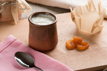 Obraz na płótnie Canvas White homemade yogurt in a clay jar with dried apricot