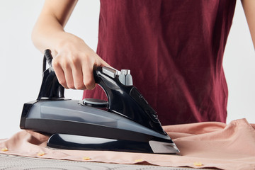 Cropped view of woman with black iron ironing shirt isolated on grey