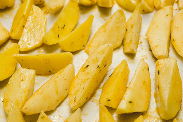 Delicious baked potatoes with rosemary on parchment, closeup. Vegetarian food. Potato country style