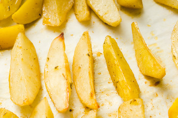 Delicious baked potatoes with rosemary on parchment, closeup. Vegetarian food. Potato country style