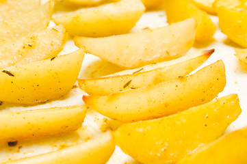 Delicious baked potatoes with rosemary on parchment, closeup. Vegetarian food. Potato country style